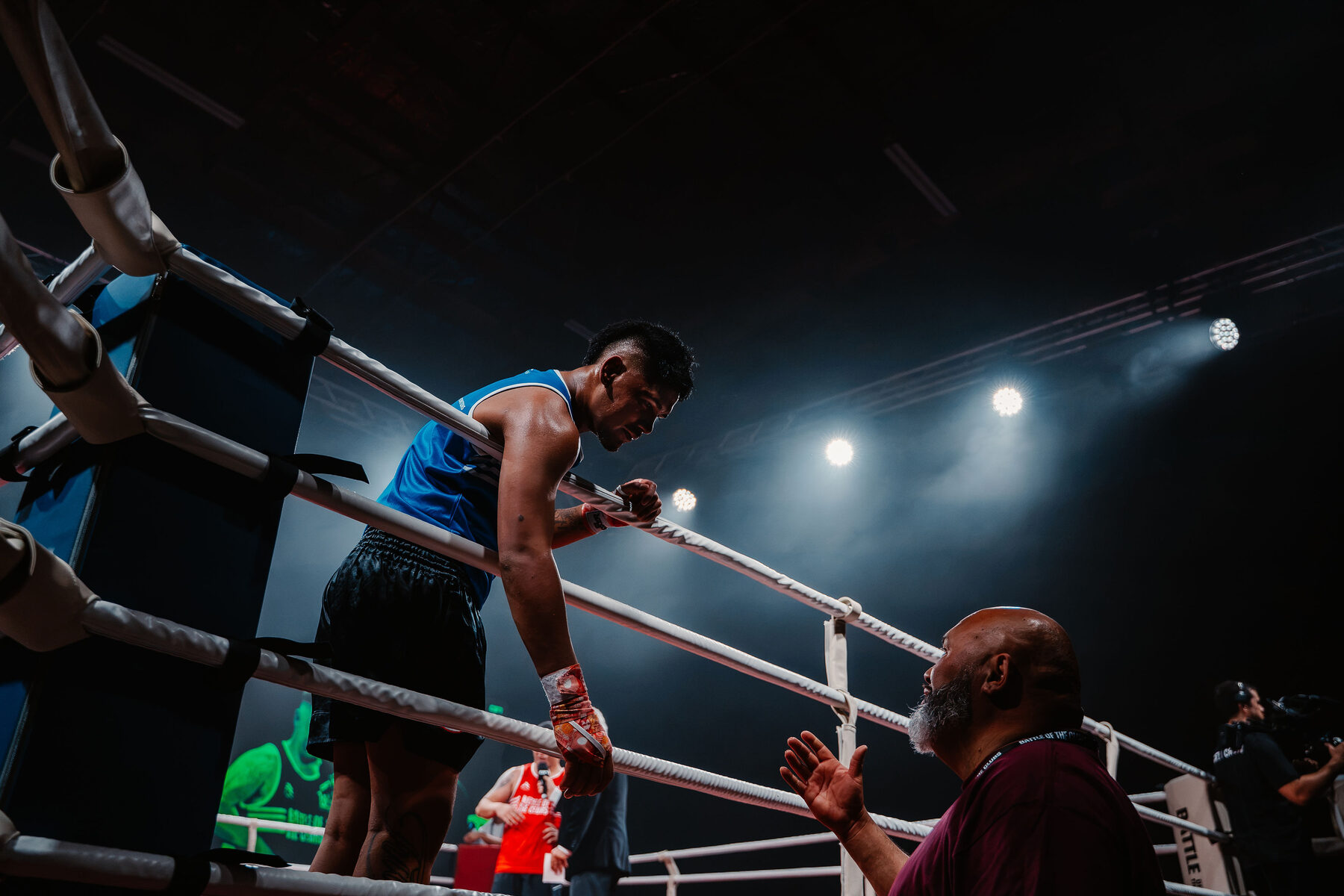 A fighter on the ropes talking to his corner